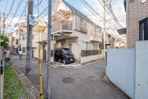 A residential street with houses, a parked car, and utility poles. - W.Hostel (Tokyo)