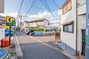 A residential street with a parking sign, houses, and parked cars. - W.Hostel (Tokyo)