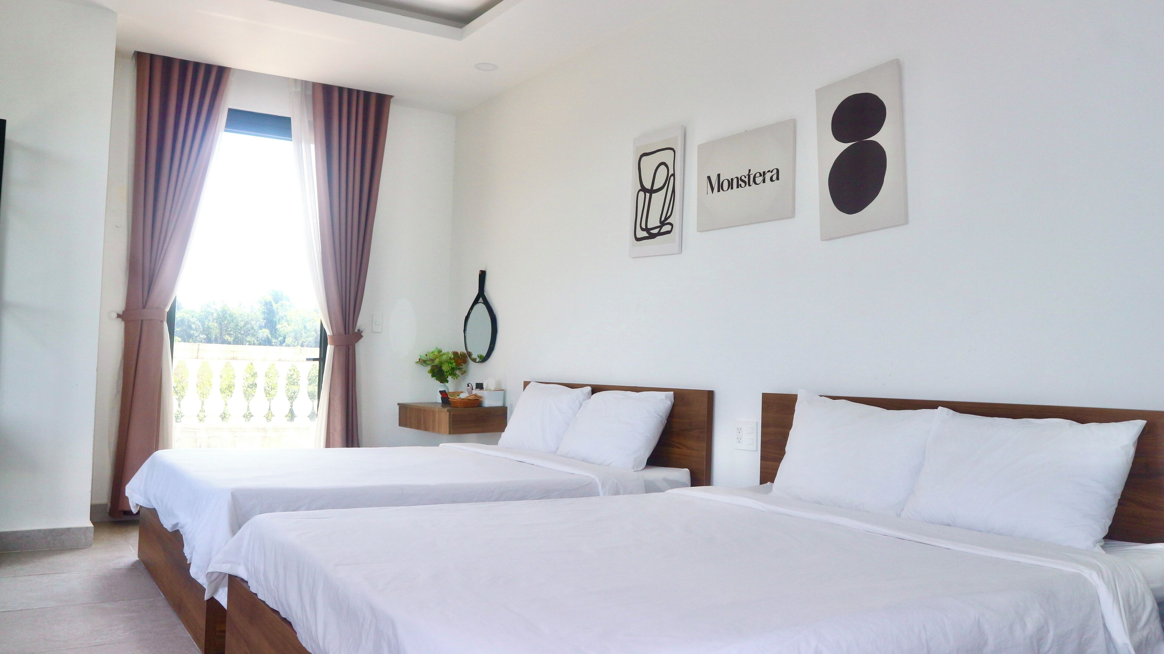 A hotel room with two beds, a balcony with curtains, a wall-mounted mirror, and artwork.