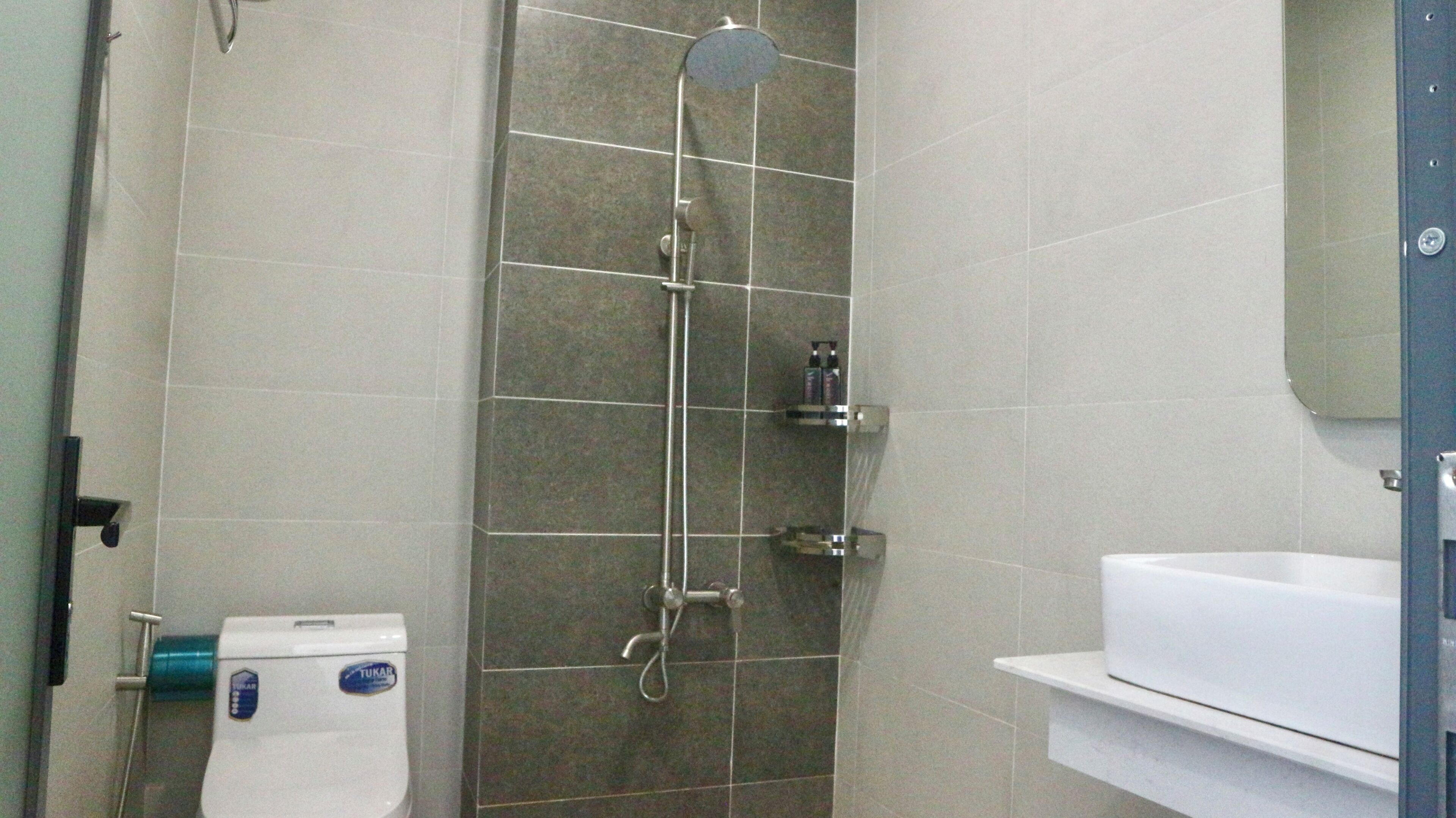 Een badkamer met douche, toilet en wastafel.