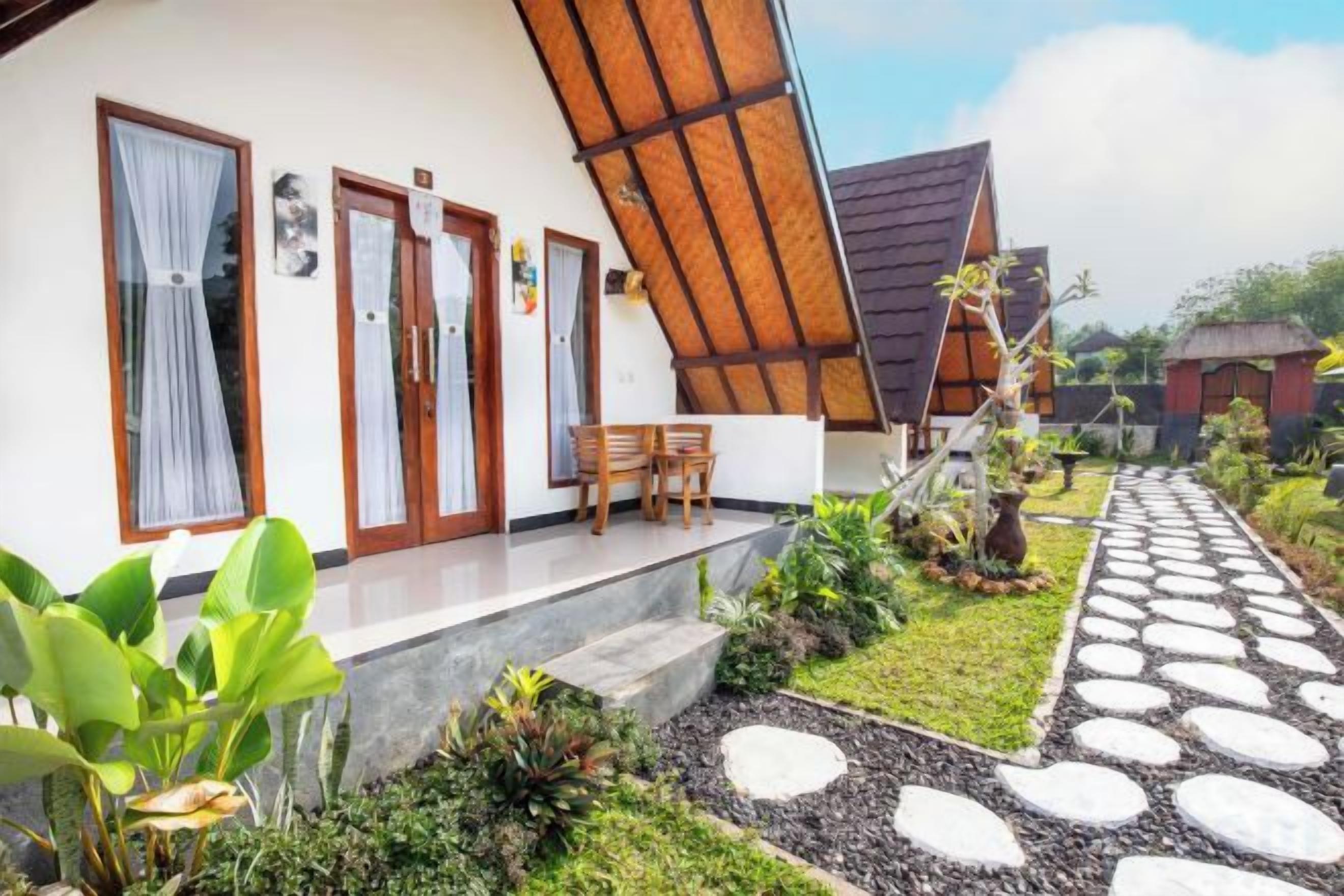 A house with a porch, a dining area, and a garden with a stone pathway.
