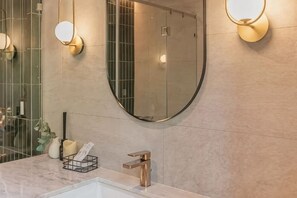 A bathroom with a round mirror, a sink, and a towel rack. - The Lai Tiny House at Mae Kampong (Mae On)