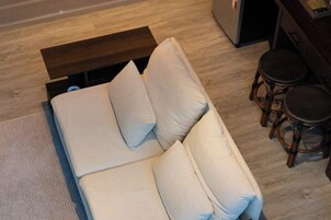 Una cama con almohadas, un cabecero de madera y una pequeña mesa con taburetes.