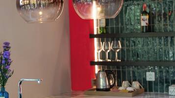 A kitchen area with a marble countertop, a vase with flowers, a coffee maker, and a wine rack with glasses.