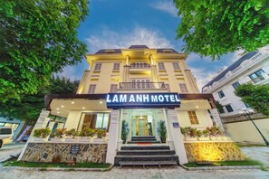 A hotel entrance with a sign reading 'LAM ANH MOTEL,' a staircase leading up to the entrance, and a well-maintained garden area. - Lam Anh Hotel 2 Duong Noi Ha Dong (Hanoi)