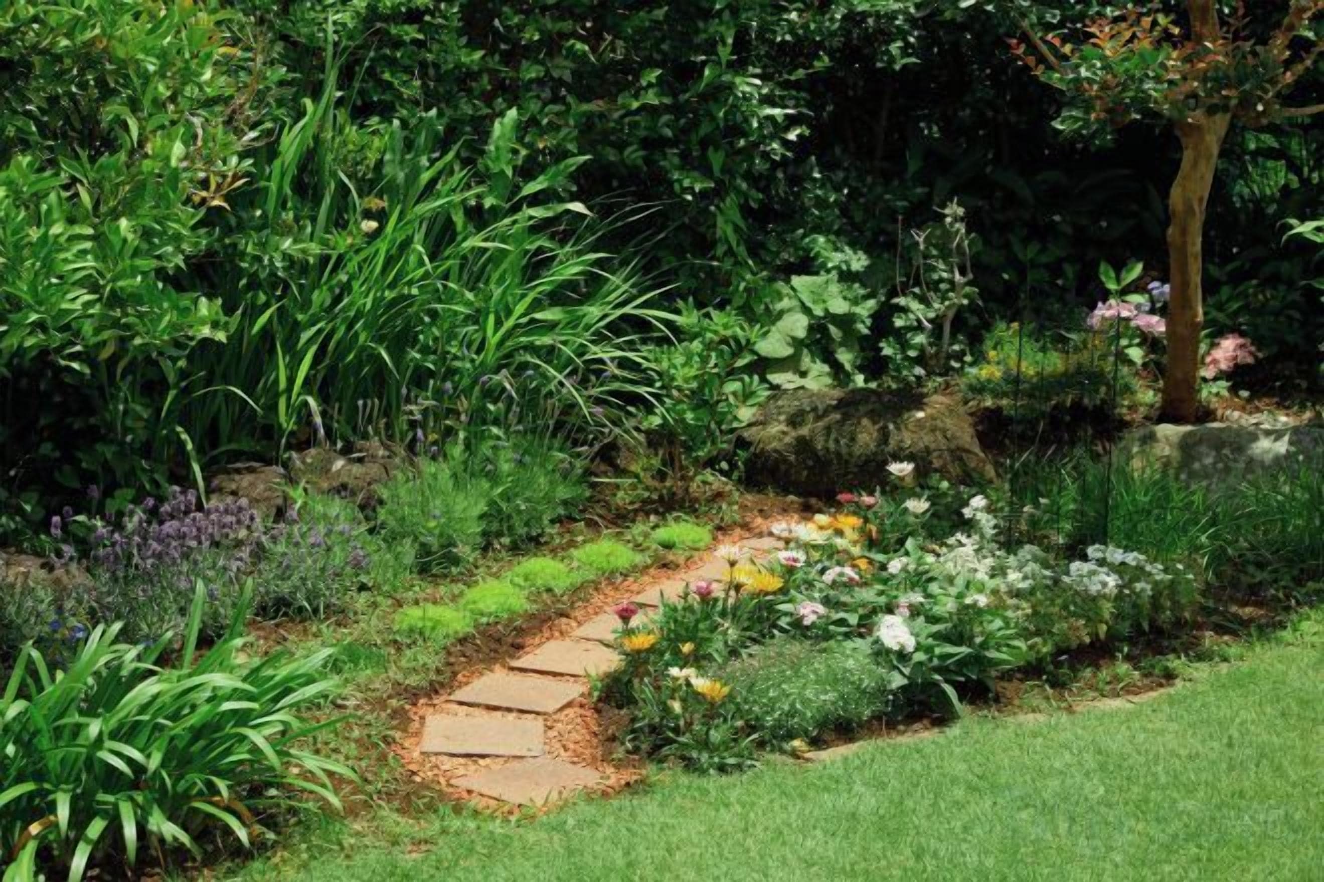 A garden with a stone pathway surrounded by various plants and flowers.