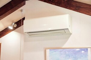 Un equipo de aire acondicionado blanco montado en una pared con una estructura de vigas de madera encima.