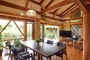 A spacious room with a wooden dining table, chairs, a TV, and large windows with curtains. - Malama Monstera - In a botanical space, pls have a relaxing time. (Isumi)