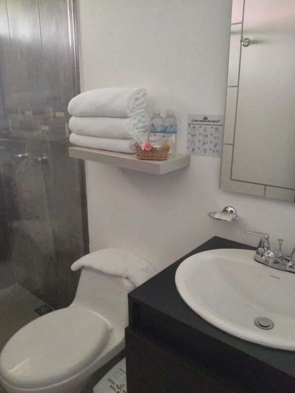 A bathroom with a toilet, sink, and a shower area. - Finca Hotel Betulia (La Tebaida)