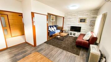 A compact living space with a sofa, a red chair, a small table, a television, and a fireplace.
