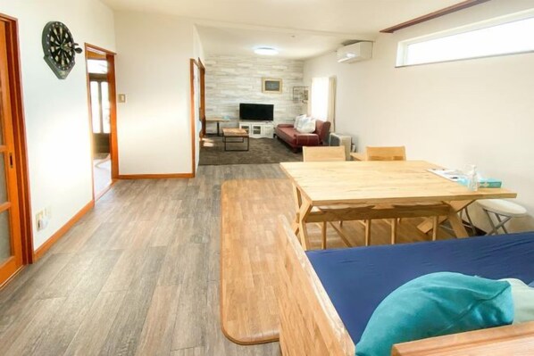 A compact living space with a dining table, a sofa, a TV, and a small kitchen area. - Port Front (Shiraoi)