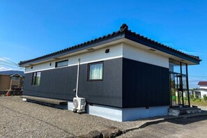 Een gebouw met twee verdiepingen, een plat dak en een overdekte veranda.