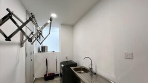 Une cuisine de taille réduite, équipée d’un évier, d’une fenêtre et d’une étagère fixée au plafond.