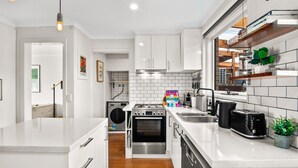 A modern kitchen with white cabinetry, a stainless steel stove, and a dishwasher.