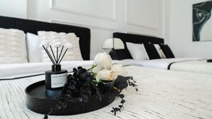 Une chambre d’hôtel avec un lit, une table de chevet agrémentée d’un diffuseur et de fleurs, et un mur orné d’un tableau.