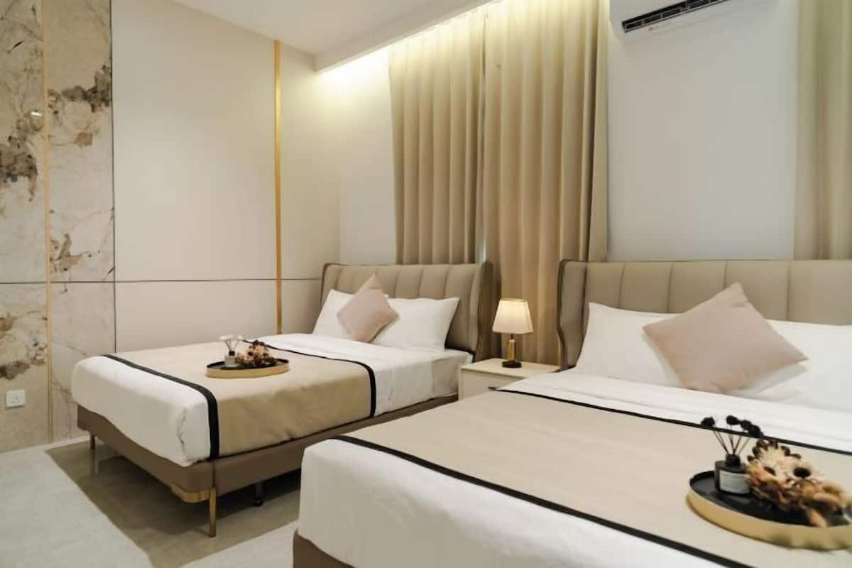 Ein Hotelzimmer mit zwei Betten, einer Marmorwand und einem großen Fenster mit Vorhängen.