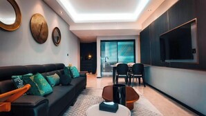 Un salon moderne avec un canapé, une table basse et des miroirs fixés au mur. On y trouve également un coin repas avec des chaises et un téléviseur fixé au mur.