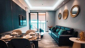 Un salon moderne comprenant un coin repas, un canapé et un téléviseur fixé au mur.