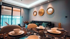Un coin repas avec une table dressée pour quatre personnes, un canapé et trois miroirs fixés au mur.