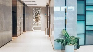 Un hall d’entrée moderne avec une cloison en verre, un comptoir d’accueil et une plante en pot.