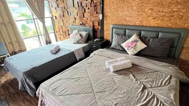 Habitación de hotel con dos camas, un muro de madera y una ventana con cortinas.