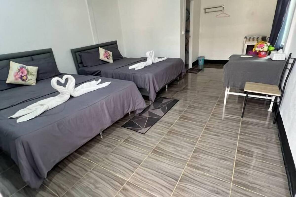 A hotel room with two beds, a small table, and a chair.