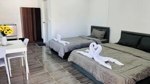 Habitación de hotel con dos camas, una mesita con un jarrón de girasoles y un panel de madera en la pared.