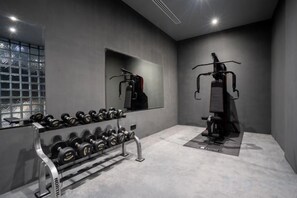 Et fitnessrum med spejl, vægtstangstativ og motionscykel.