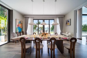 A dining room with a large table, chairs, and pendant lights. - 6BR Oceanfront Luxury Villa 30m Infinity Pool Villa Serenity Warm Plus (Phuket)