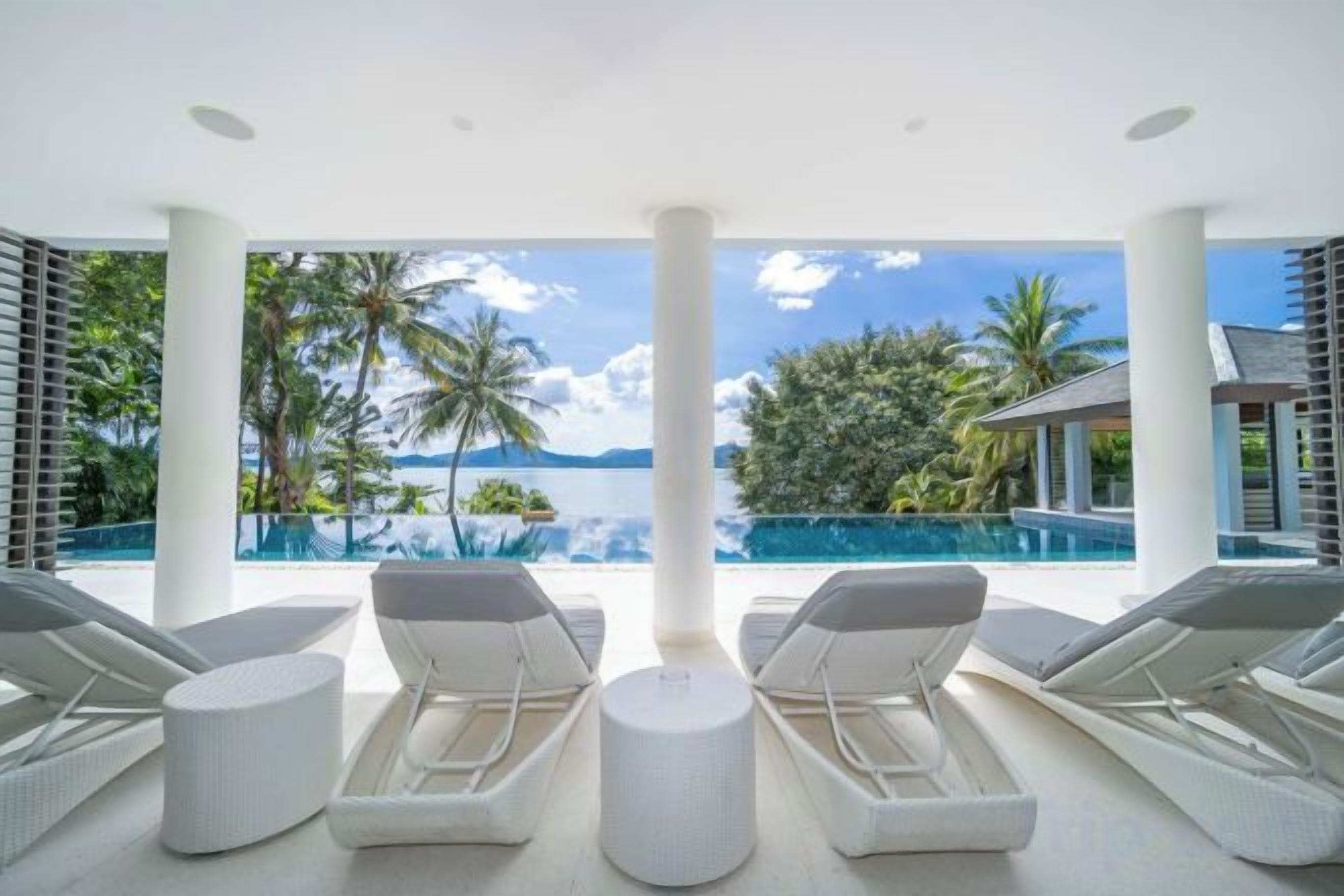 A poolside area with lounge chairs and a view of the ocean.