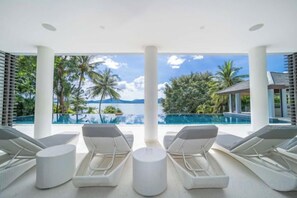 A poolside area with lounge chairs and a view of the ocean. - 6BR Oceanfront Luxury Villa 30m Infinity Pool Villa Serenity Warm Plus (Phuket)