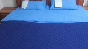 Una cama con ropa de cama azul y una colcha azul acolchada.
