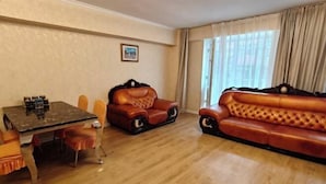 Una habitación con una mesa de comedor, dos sofás de cuero y una ventana con cortinas.