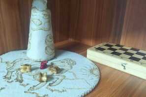 A chessboard and a small figurine on a round table with a patterned tablecloth. - OYU (Ulaanbaatar)