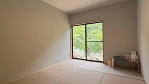 A room with tatami flooring, a sliding door with a view of greenery, and a small table with a kettle. - SEN.RETREAT TAKIJIRI (Tanabe)