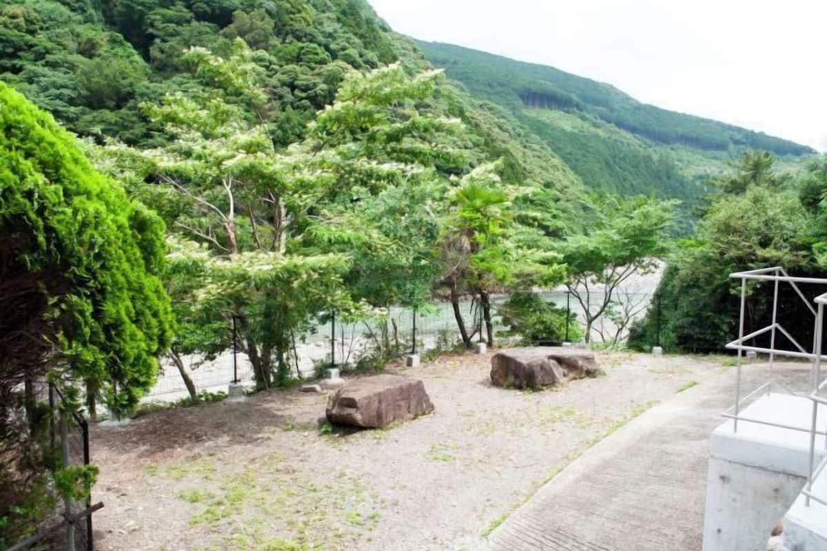 A natural landscape with a river, trees, and rocks.