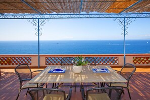 A table with chairs and a potted plant, overlooking the sea. - Respiro del Mare (Sorrento)
