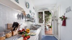 A modern kitchen with a white backsplash, stainless steel appliances, and a variety of fresh produce on the counter. - Respiro del Mare (Sorrento)