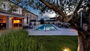 A pool area with lounge chairs, a swimming pool, and a building with a stone facade. - Villa with pool und jacuzzi, 8 Persons, parking, near Porec (Nova Vas)