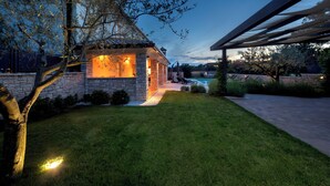 A stone house with a covered patio, a swimming pool, and a well-maintained lawn. - Villa with pool und jacuzzi, 8 Persons, parking, near Porec (Nova Vas)