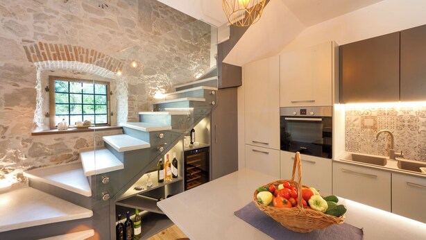 A modern kitchen with a stone wall, a built-in wine rack, and a basket of fresh produce on the island. - Villa with pool und jacuzzi, 8 Persons, parking, near Porec (Nova Vas)