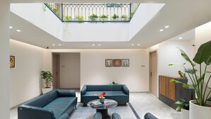A modern interior with a blue sofa set, a round coffee table, and a balcony with plants. - Champion Prime-My Downtown Hotel (Udaipur)