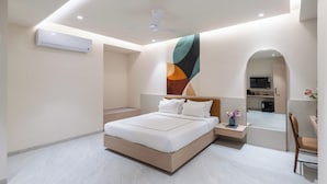 A modern bedroom with a large bed, a ceiling fan, and a built-in kitchen area visible through an archway. - Champion Prime-My Downtown Hotel (Udaipur)