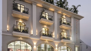 A multi-story hotel with balconies, large arched windows, and a sign reading "Chambion Prime." - Champion Prime-My Downtown Hotel (Udaipur)