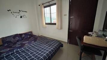 A bedroom with a bed, a desk, a chair, a window with curtains, and a door.