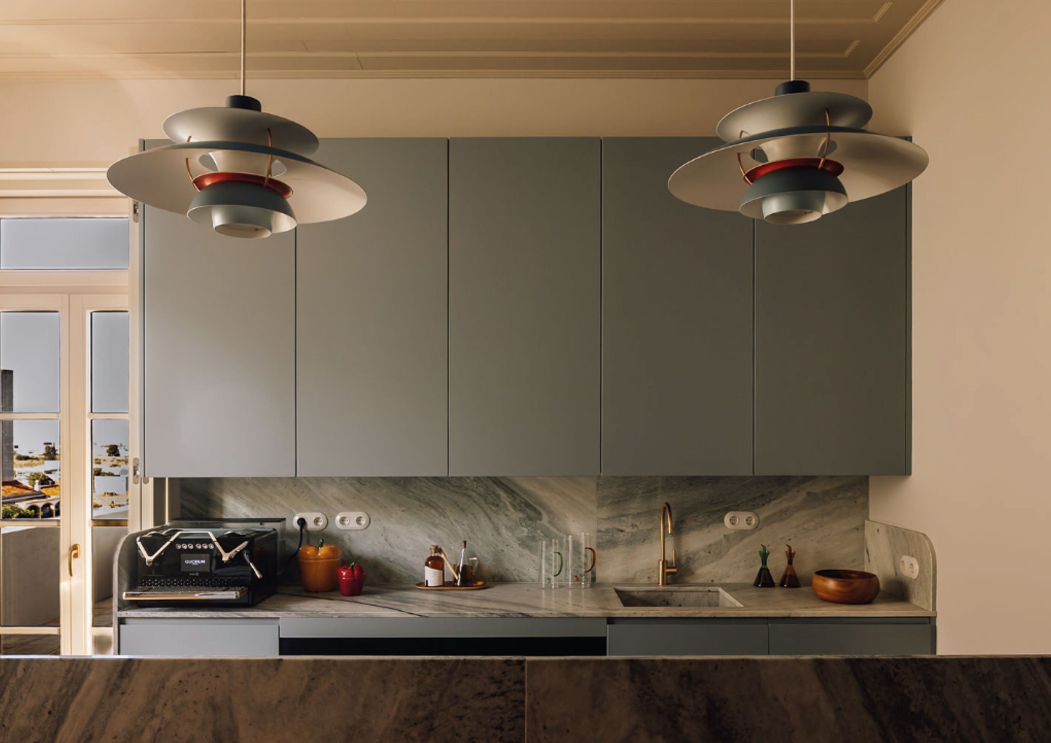 A modern kitchen with two pendant lights, a marble backsplash, and a built-in oven.