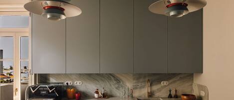 A modern kitchen with two pendant lights, a marble backsplash, and a built-in oven.