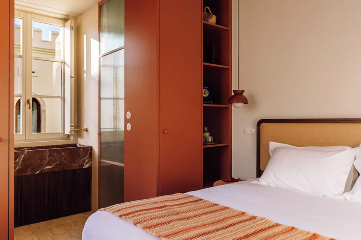 Ein Hotelzimmer mit Bett, Kleiderschrank, Schminktisch mit Spiegel und Ablage für Toilettenartikel.