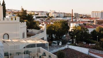 Terraço no telhado com área de estar externa, vista da paisagem urbana e céu claro.