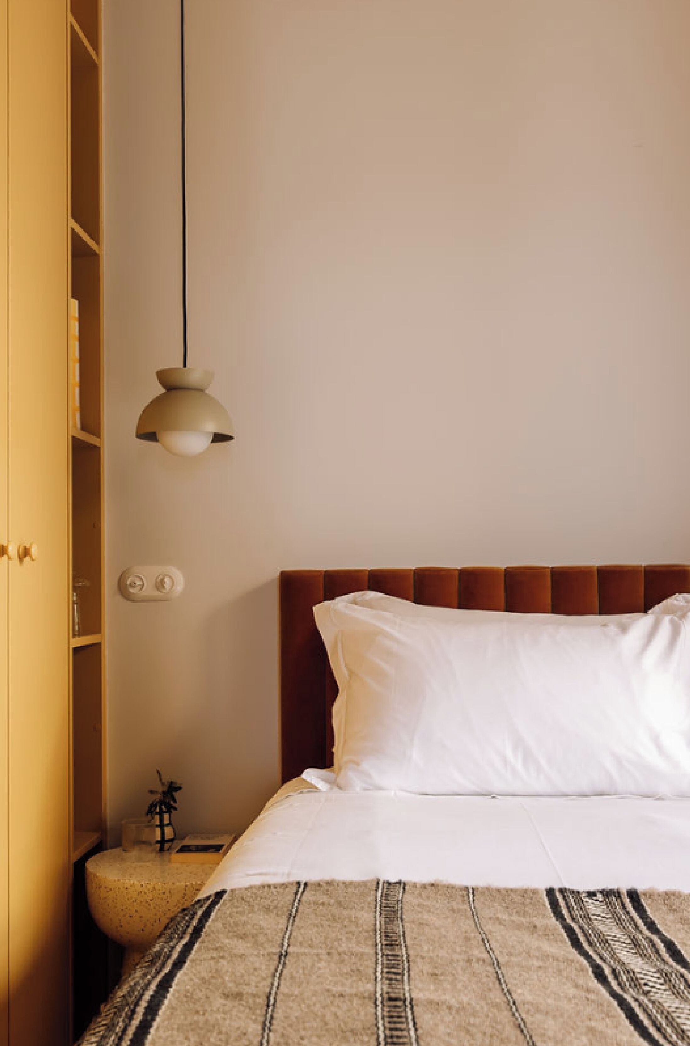 A bedroom with a bed, a bedside table, a lamp, and a wardrobe.